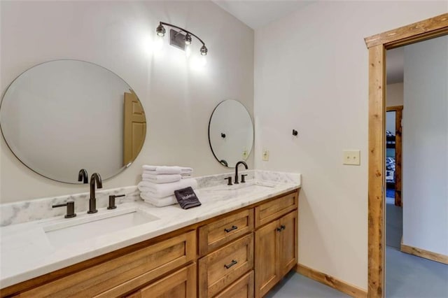 full bathroom featuring double vanity, a sink, and baseboards