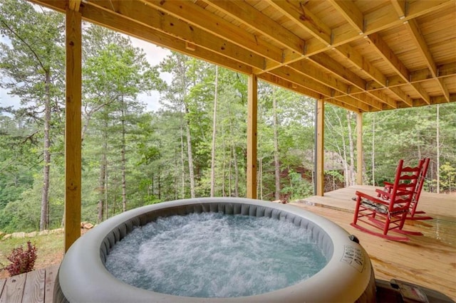 view of patio featuring a wooden deck, an outdoor hot tub, and a view of trees