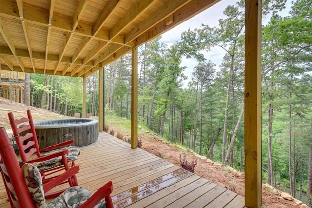 deck with a hot tub and a wooded view