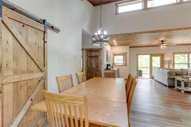 dining space with wood finished floors, a healthy amount of sunlight, wooden ceiling, and a barn door