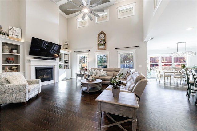 living room featuring ceiling fan, a towering ceiling, and dark hardwood / wood-style floors