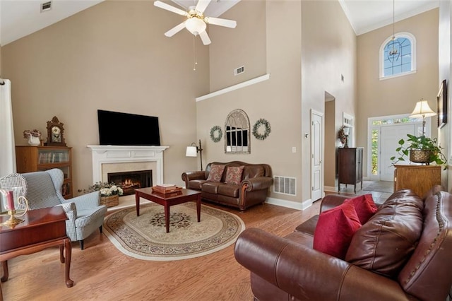 1125 Fairview Club Cir, Dacula, GA 30019 - living area featuring a high ceiling, ceiling fan, wood finished floors, a warm lit fireplace, and healthy amount of natural light
