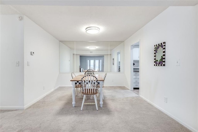 dining space featuring light colored carpet and baseboards