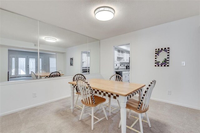 dining space with light carpet, a textured ceiling, and baseboards