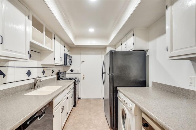 kitchen featuring a sink, white cabinetry, black appliances, washer / clothes dryer, and a raised ceiling