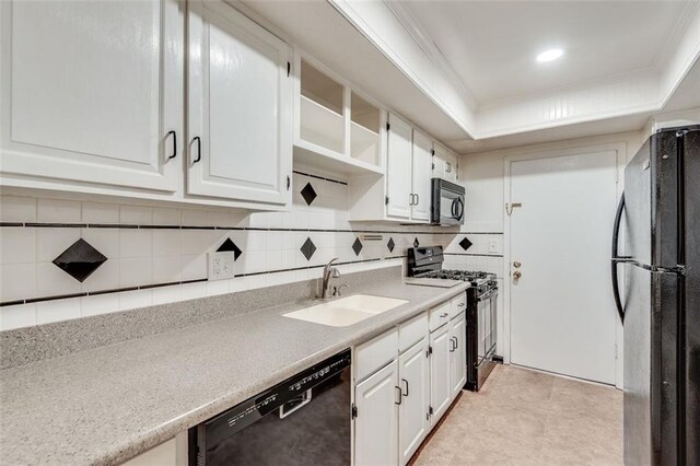 kitchen featuring a raised ceiling, white cabinetry, a sink, and black appliances