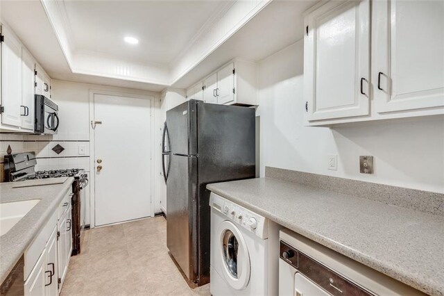 kitchen featuring black appliances, washer / clothes dryer, light countertops, and a tray ceiling