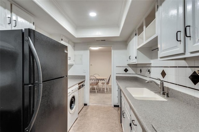 kitchen with a sink, freestanding refrigerator, decorative backsplash, a raised ceiling, and washer / dryer