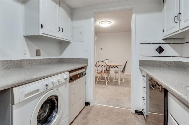 clothes washing area featuring cabinet space, light colored carpet, and washer and dryer