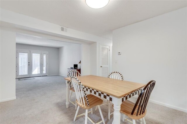 dining area featuring baseboards, french doors, and light colored carpet