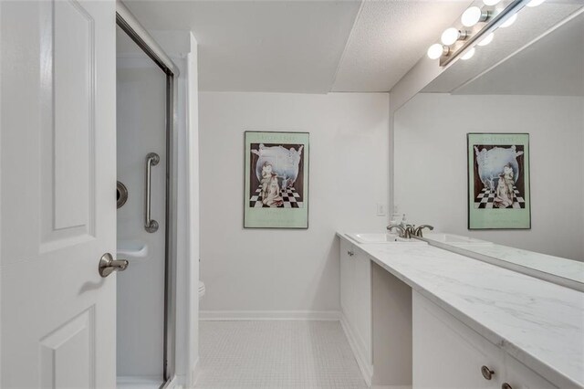 full bath with a stall shower, tile patterned flooring, vanity, and baseboards