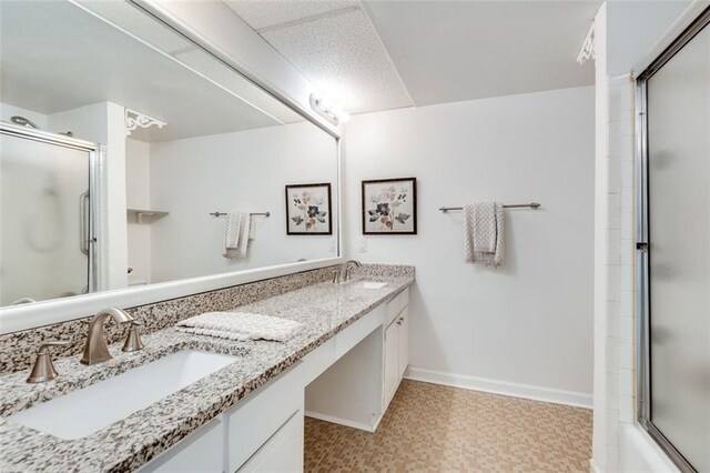 bathroom featuring an enclosed shower, tile patterned floors, a sink, and baseboards