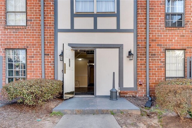 entrance to property featuring stucco siding and brick siding