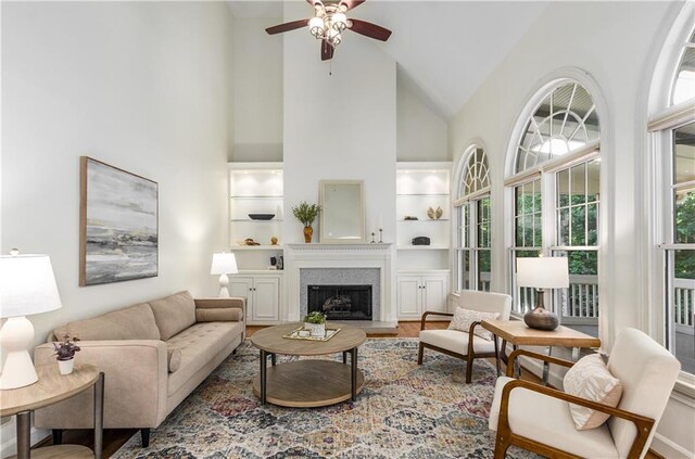 4679 Glenshire Pl, Dunwoody, GA 30338 - living room with high vaulted ceiling, ceiling fan, a fireplace with raised hearth, built in features, and wood finished floors