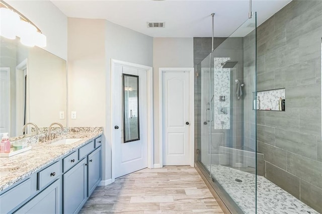 bathroom with vanity, hardwood / wood-style flooring, and a shower with door