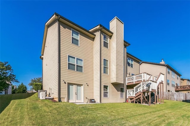 rear view of property featuring a wooden deck, a lawn, and central AC