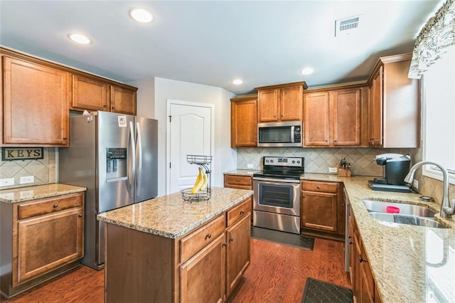 kitchen featuring stainless steel appliances, sink, light stone countertops, a kitchen island, and dark hardwood / wood-style flooring