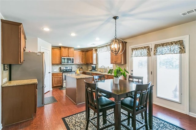 kitchen featuring appliances with stainless steel finishes, dark wood-type flooring, light stone counters, and plenty of natural light