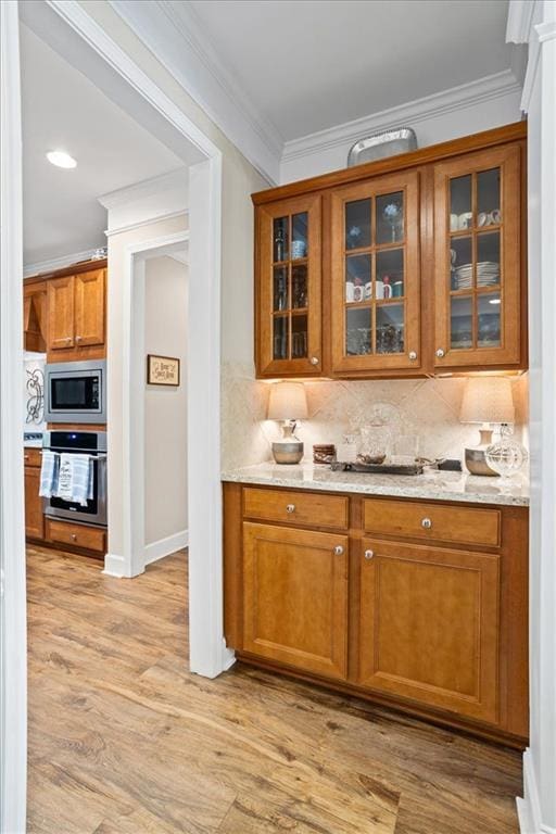 218 Begonia Ct, Griffin, GA 30223 - bar with appliances with stainless steel finishes, tasteful backsplash, light wood-style flooring, and crown molding