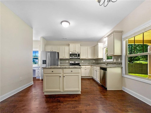 kitchen with tasteful backsplash, light stone counters, stainless steel appliances, a center island, and dark hardwood / wood-style floors