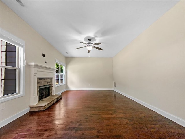 unfurnished living room featuring a stone fireplace, ceiling fan, and dark hardwood / wood-style flooring