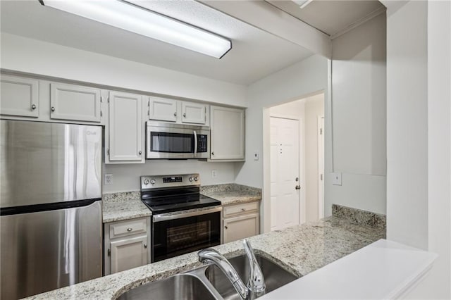 kitchen with light stone countertops, stainless steel appliances, and a sink