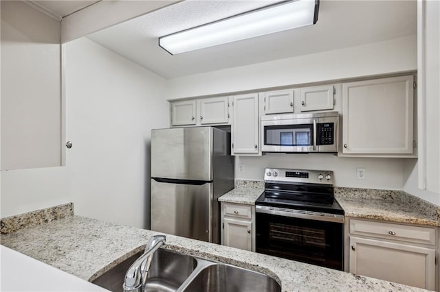 kitchen with stainless steel appliances, a sink, and light stone countertops