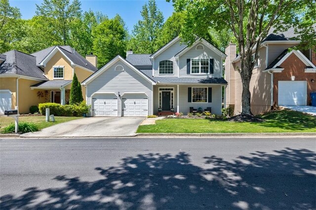 traditional home featuring driveway, a garage, and a front lawn