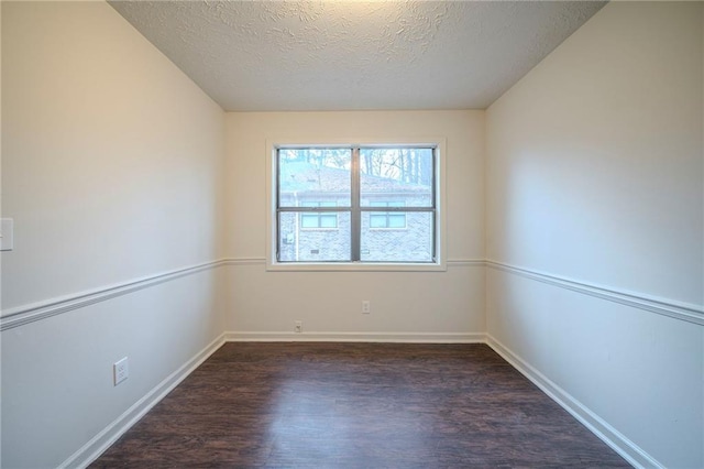 empty room with dark wood-type flooring and a textured ceiling