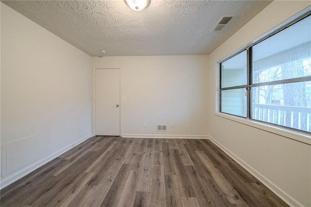 unfurnished room with dark hardwood / wood-style floors and a textured ceiling