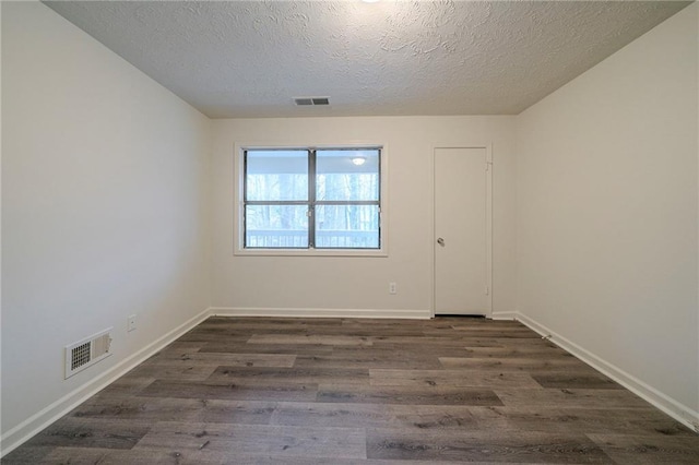 unfurnished room featuring dark wood-type flooring and a textured ceiling