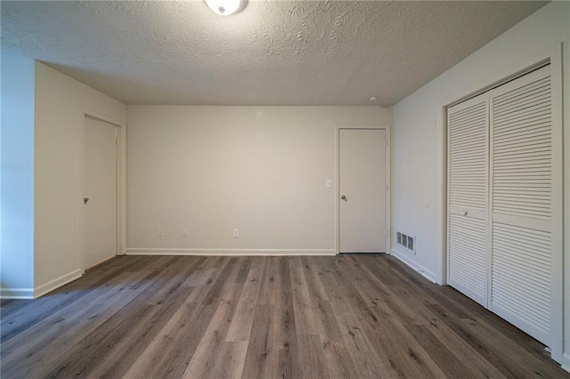 unfurnished bedroom featuring dark hardwood / wood-style flooring, a closet, and a textured ceiling