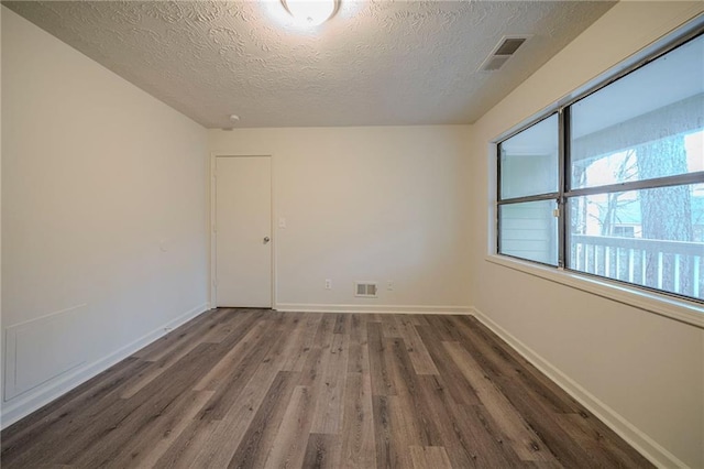 unfurnished room featuring dark hardwood / wood-style flooring and a textured ceiling