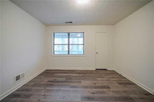 empty room featuring dark hardwood / wood-style flooring and a textured ceiling