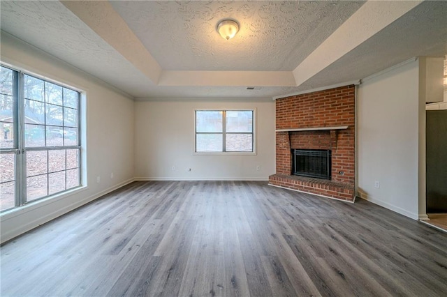 unfurnished living room with wood-type flooring, a textured ceiling, a fireplace, and a tray ceiling