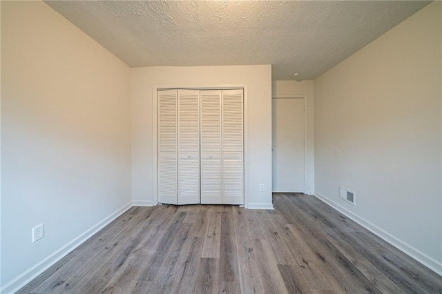 unfurnished bedroom featuring a textured ceiling, light hardwood / wood-style floors, and a closet