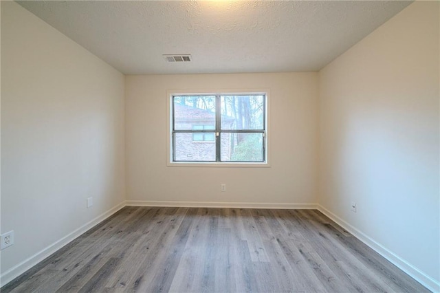 unfurnished room featuring light hardwood / wood-style flooring and a textured ceiling