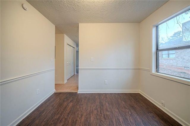 unfurnished room with dark hardwood / wood-style floors and a textured ceiling