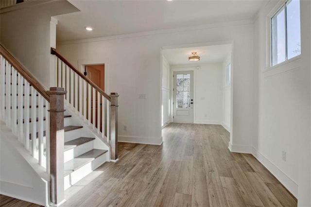 entrance foyer with ornamental molding and light hardwood / wood-style floors