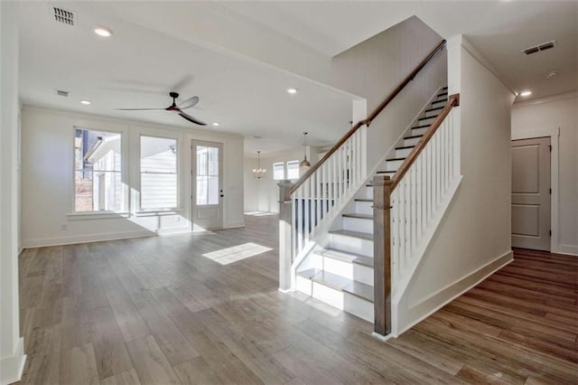 foyer entrance featuring hardwood / wood-style flooring, ornamental molding, and ceiling fan with notable chandelier