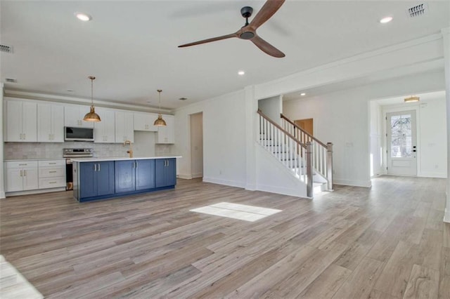 kitchen with stainless steel appliances, white cabinetry, a kitchen island, and pendant lighting