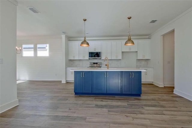 kitchen featuring white cabinetry, blue cabinetry, an island with sink, and appliances with stainless steel finishes