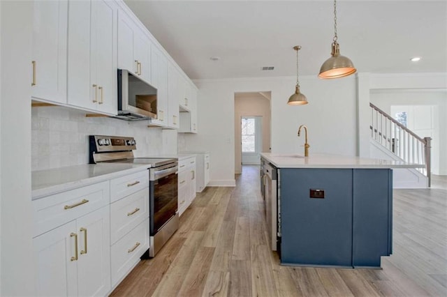 kitchen with decorative light fixtures, white cabinets, backsplash, a kitchen island with sink, and stainless steel appliances