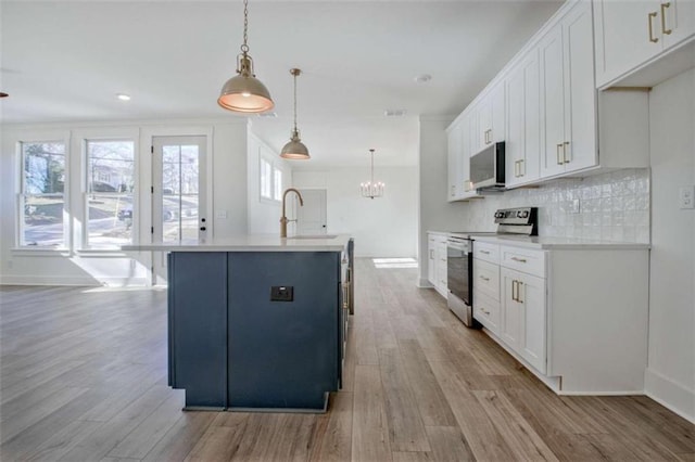 kitchen featuring pendant lighting, an island with sink, sink, white cabinets, and stainless steel appliances