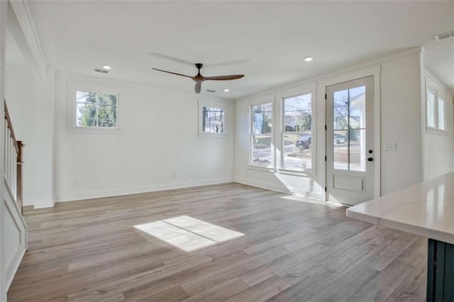 unfurnished living room featuring a wealth of natural light, ceiling fan, and light wood-type flooring