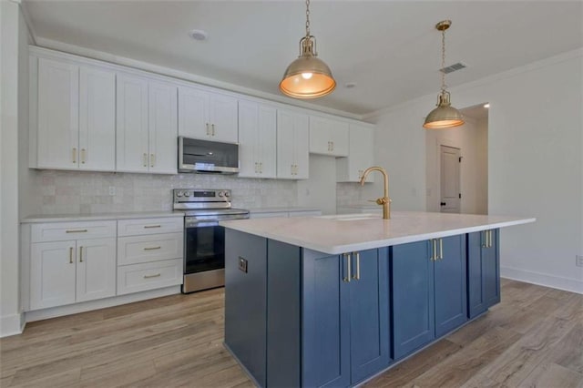 kitchen with sink, hanging light fixtures, stainless steel appliances, an island with sink, and white cabinets