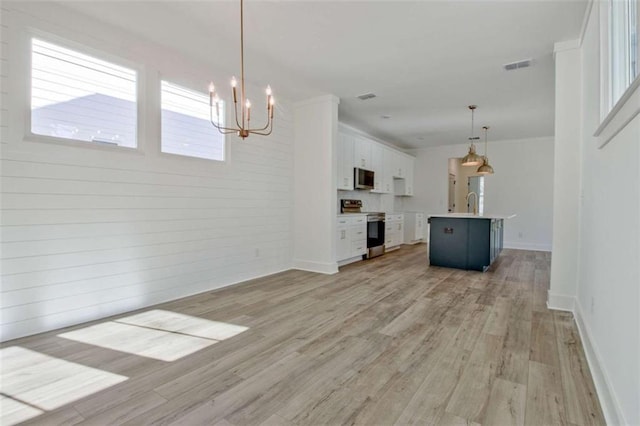 unfurnished living room with light wood-type flooring and a notable chandelier