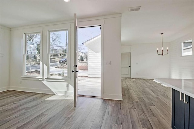 doorway with an inviting chandelier and light hardwood / wood-style floors