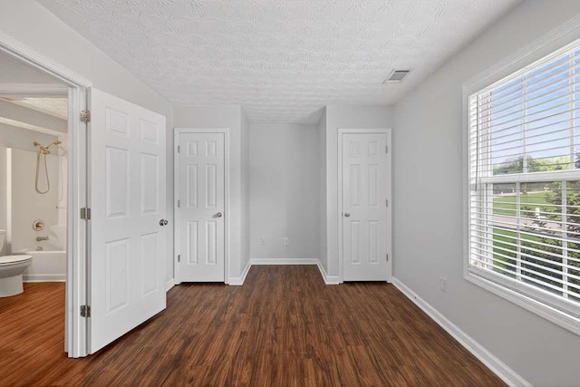 563 Bailey Dr, Jefferson, GA 30549 - unfurnished bedroom with dark wood finished floors, multiple windows, a textured ceiling, and ensuite bath