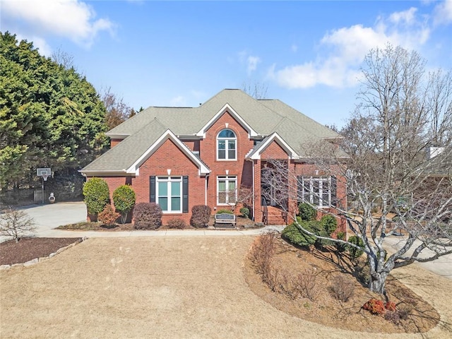 traditional-style home featuring brick siding and roof with shingles